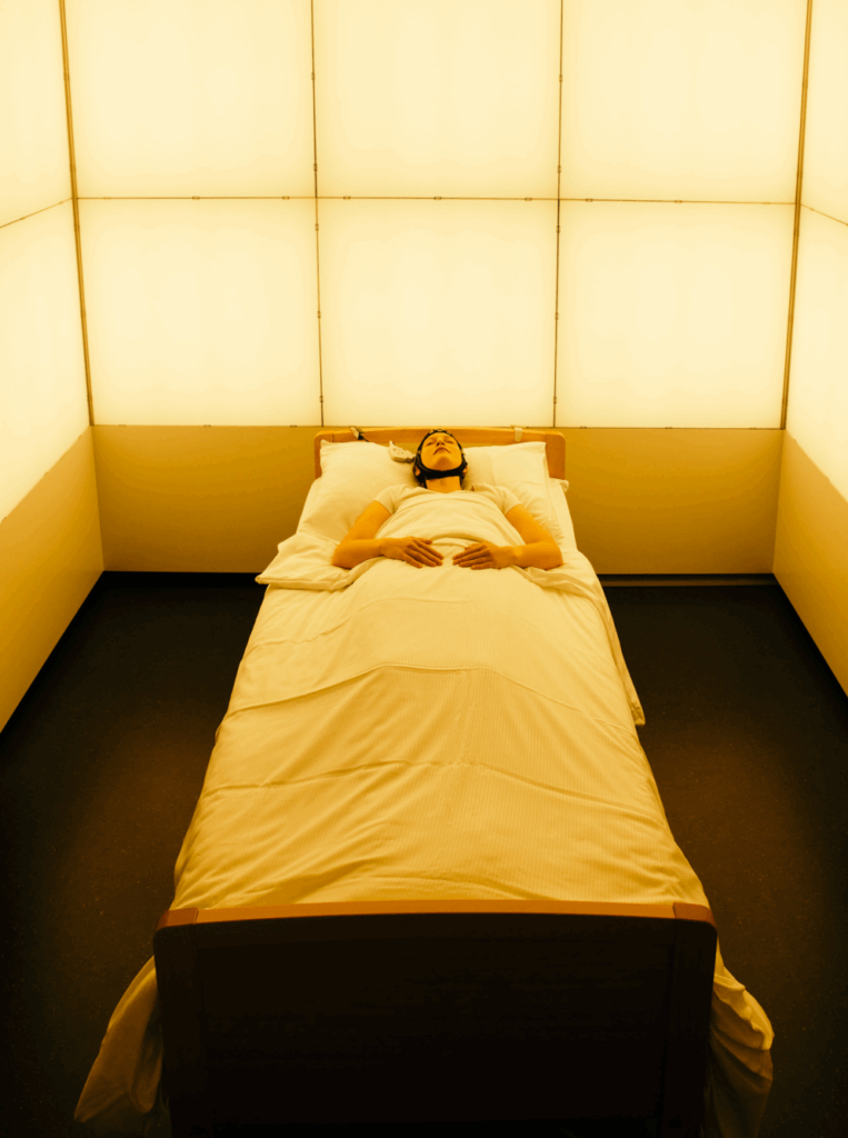 a person lying on a bed with a measuring device attached to their head