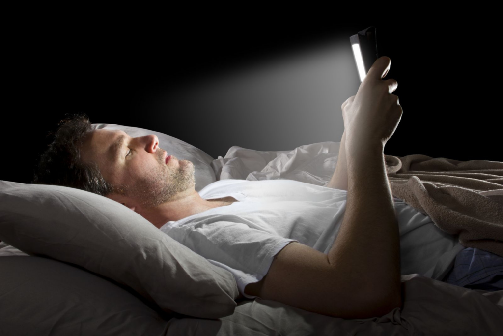a man looking at his phone in bed